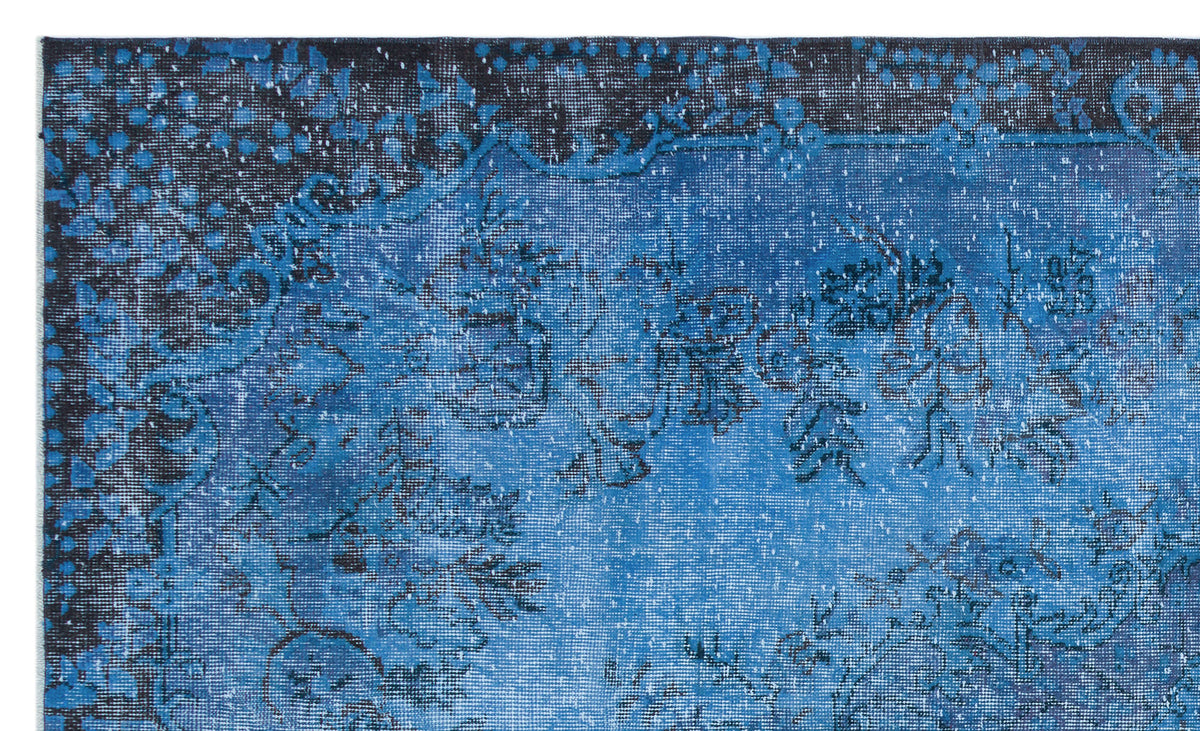 Deep blue and black distressed rug with a faded traditional floral medallion pattern.