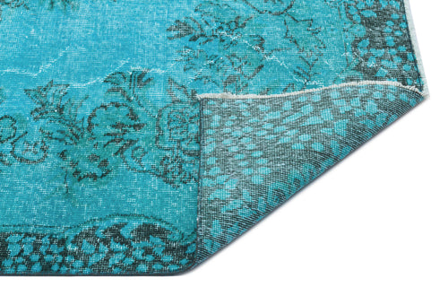 Load image 1 in gallery view. Turquoise and black distressed rug with a floral medallion pattern, shown with a folded corner on a white background.