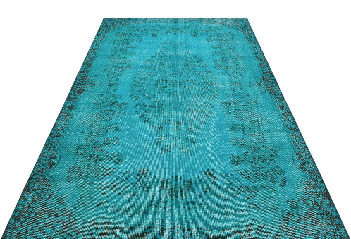 Turquoise distressed rug with a dark charcoal floral medallion and border pattern on a white background.