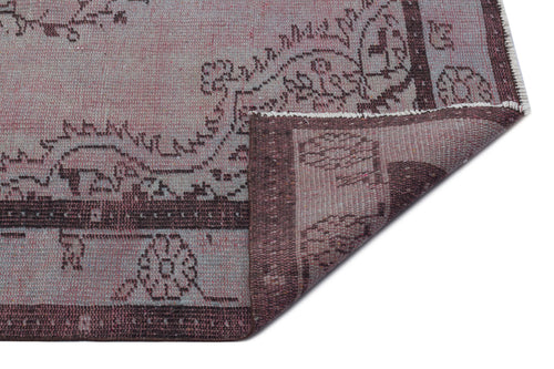 Load image 1 in gallery view. Muted mauve and dark brown traditional rug with a floral medallion pattern, shown with a corner folded over.