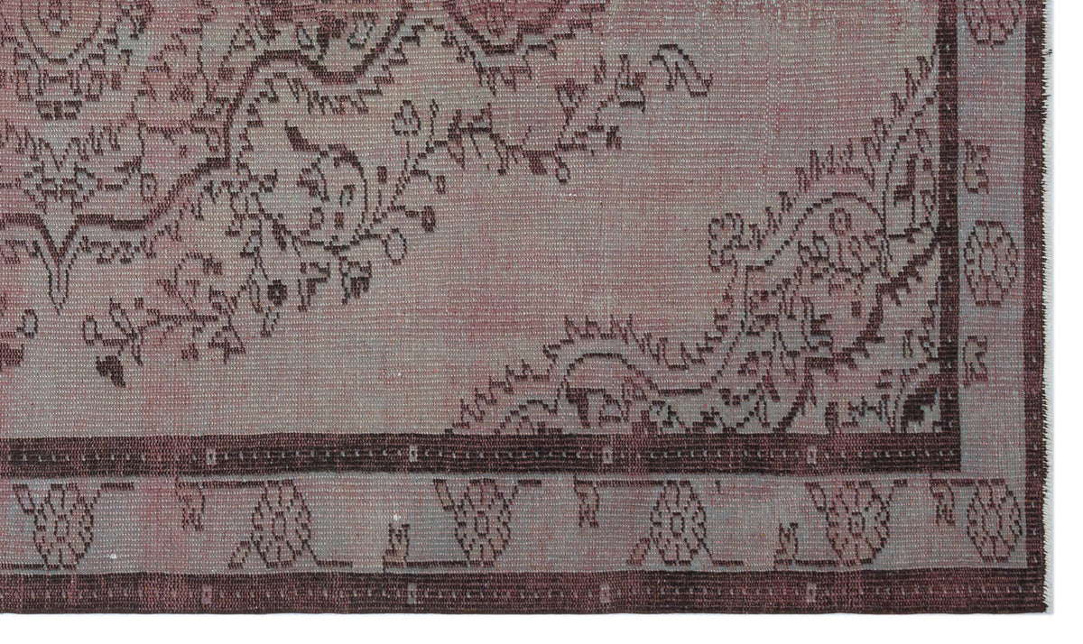 Dusty rose and grey vintage-style rug with a dark brown floral border and distressed traditional pattern.