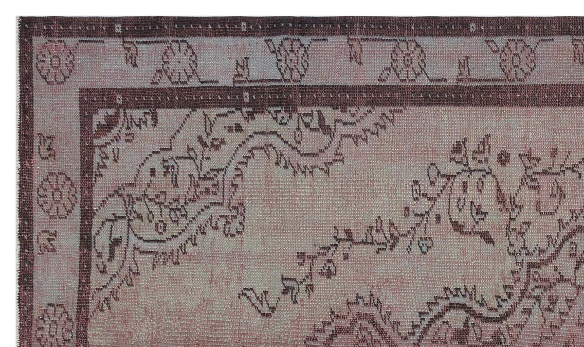 Muted mauve and dark brown rug with a distressed traditional floral border and vine pattern.