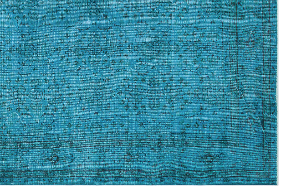 Teal distressed rug with a dark blue traditional floral medallion pattern and a bordered edge.