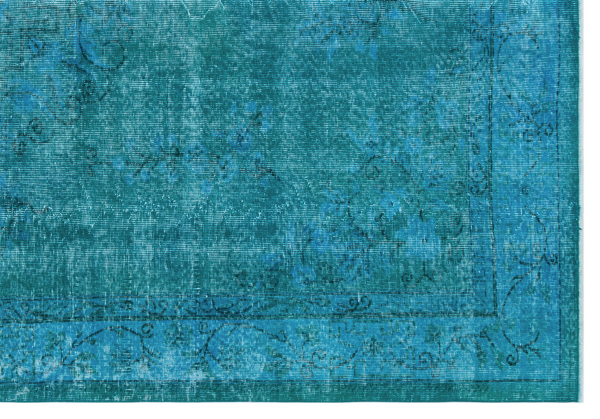 Teal distressed rug with a faded floral medallion pattern and a decorative border.