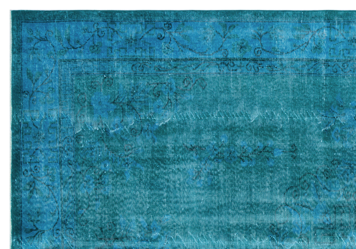 Teal distressed rug with a faded floral border and central vine pattern.