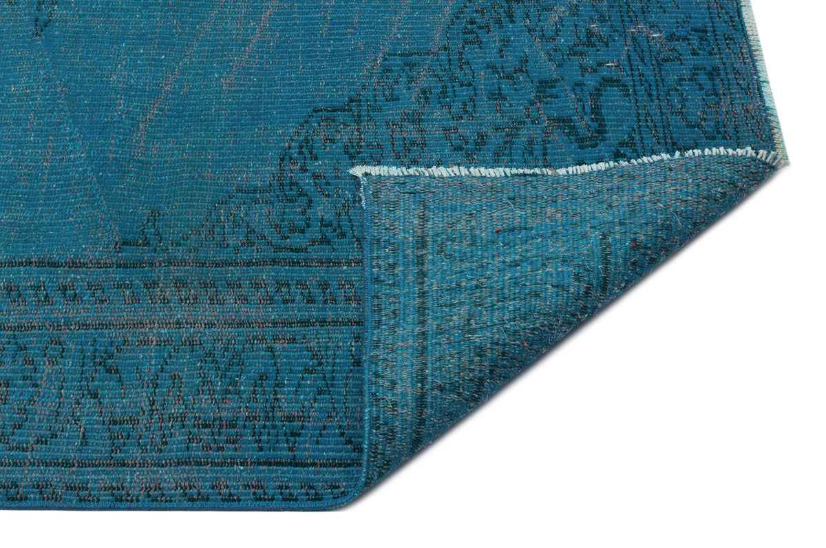 Teal distressed rug with a dark grey traditional border pattern, shown with a corner folded over on a white background.