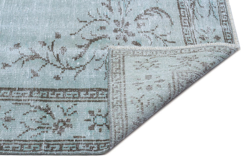 Load image 1 in gallery view. Light blue and brown distressed rug with a floral medallion pattern and a folded corner showing the woven backing.