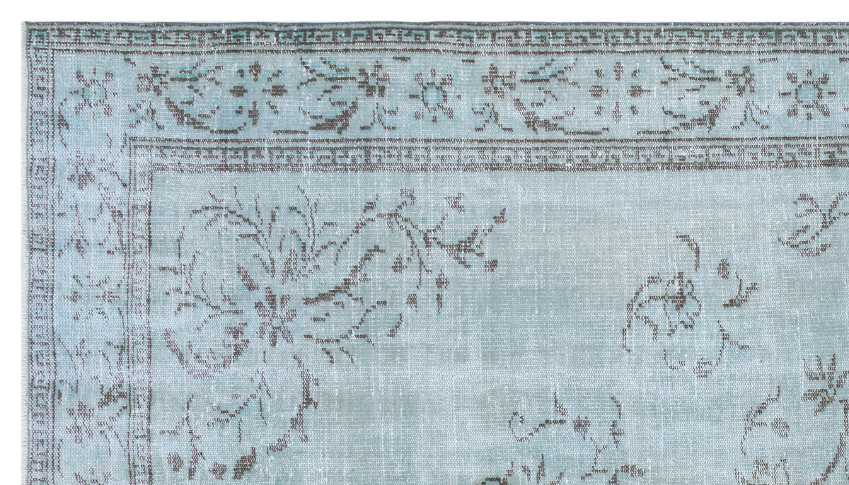 Light blue and grey distressed rug with a traditional floral medallion pattern and a geometric border.
