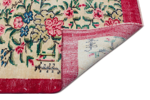 Load image 1 in gallery view. Cream rug with a floral pattern in red, blue, and green, featuring a wide red border and a folded corner.