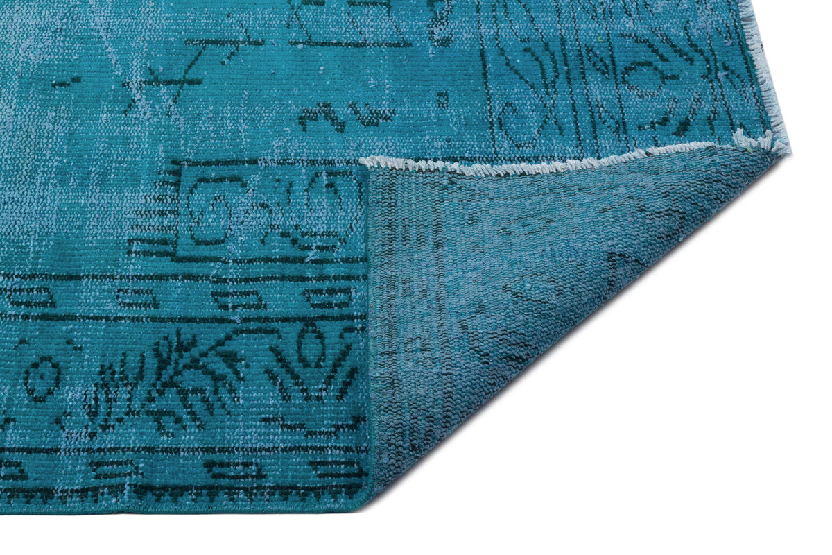 Teal distressed rug with a faded traditional pattern and a folded corner showing the textured underside.