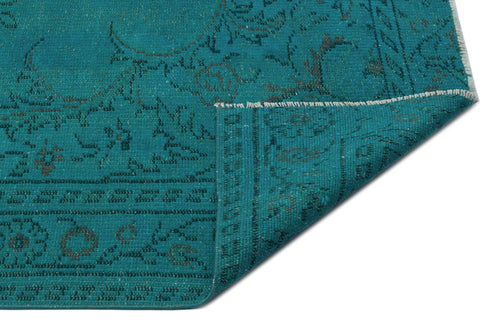 Load image 1 in gallery view. Teal rug with a dark grey distressed floral pattern, shown with a folded corner on a white background.