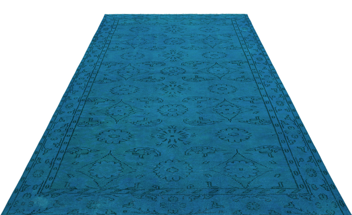 Bright blue rug with a dark, repeating floral medallion and geometric border pattern on a white background.