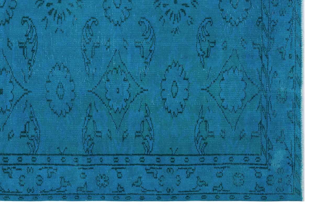 Bright blue rug with a dark blue distressed floral medallion pattern and a geometric border.
