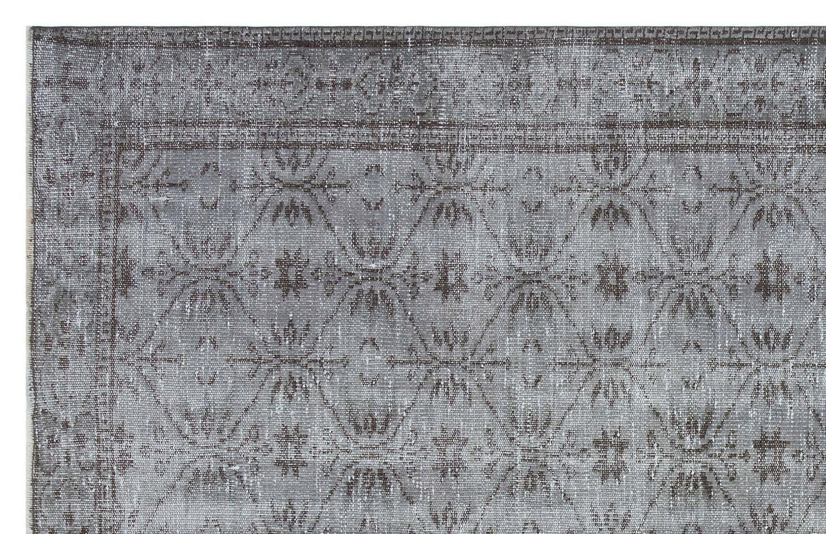 Grey and charcoal distressed rug with a repeating geometric diamond and floral medallion pattern.