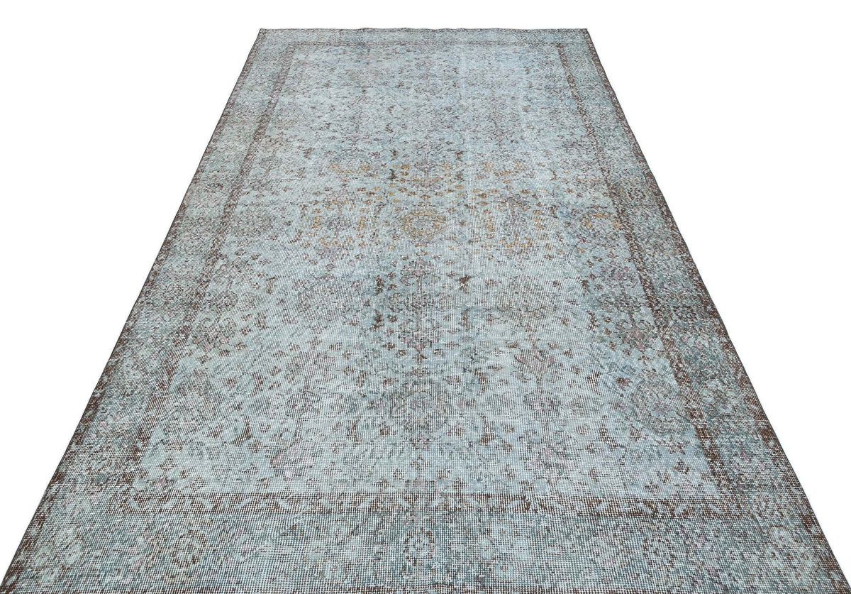 Light blue and brown distressed vintage-style rug with a traditional floral medallion pattern on a white background.