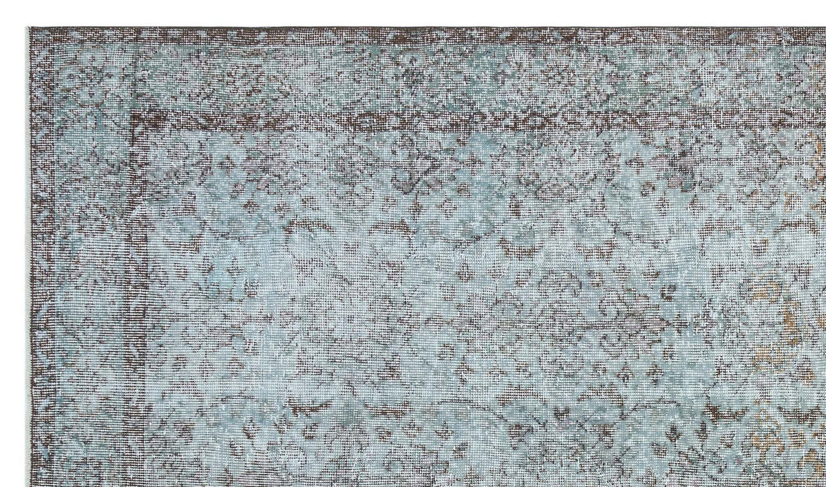 Light blue and brown distressed rug with a traditional floral medallion pattern and a wide decorative border.