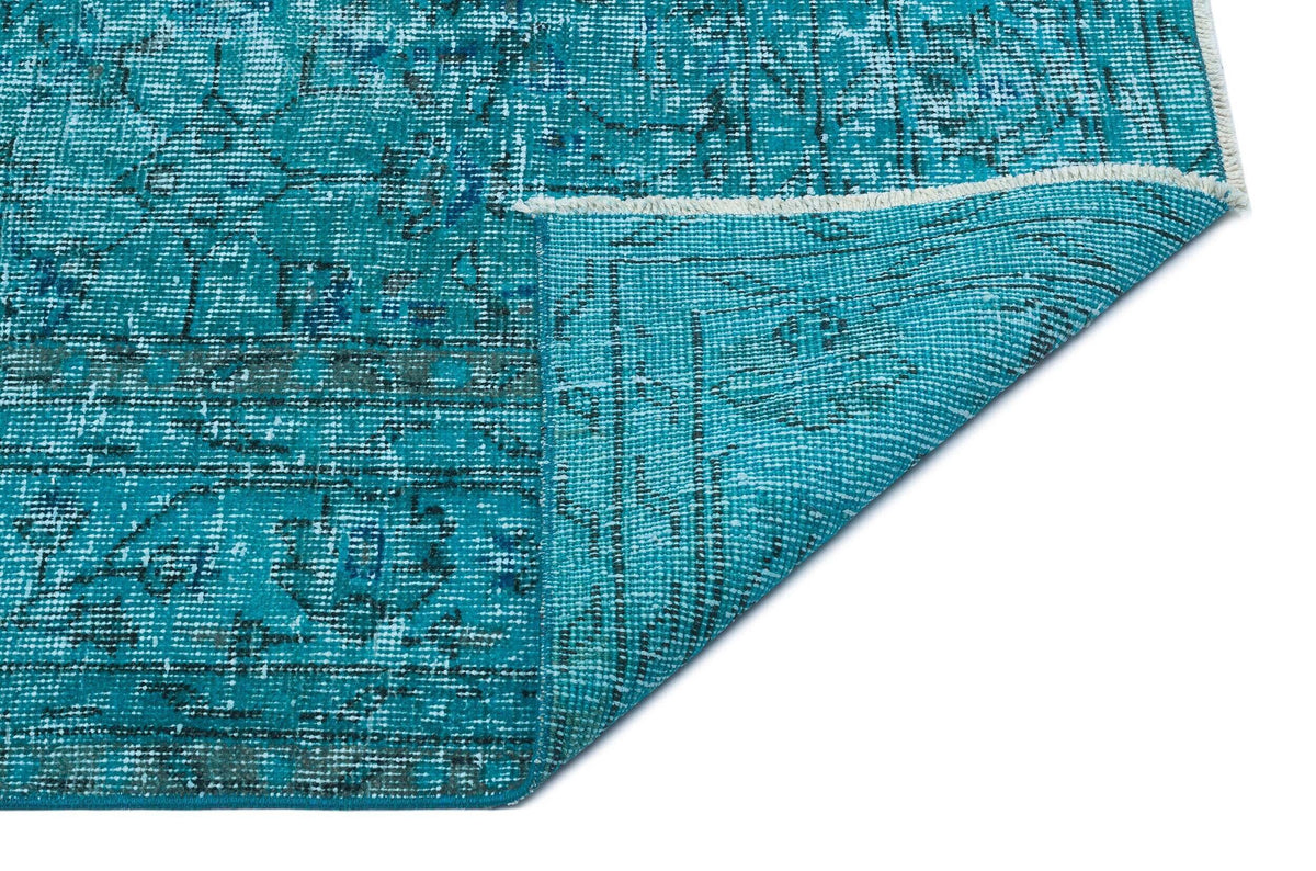 Teal and black distressed traditional rug with a folded corner revealing the underside on a white background.