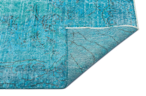 Load image 1 in gallery view. Bright turquoise distressed rug with a faded black floral pattern and a folded corner showing the underside.