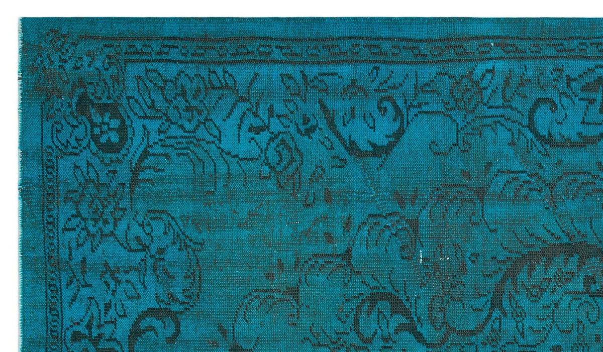 Teal rug with a black distressed floral pattern and a traditional border.