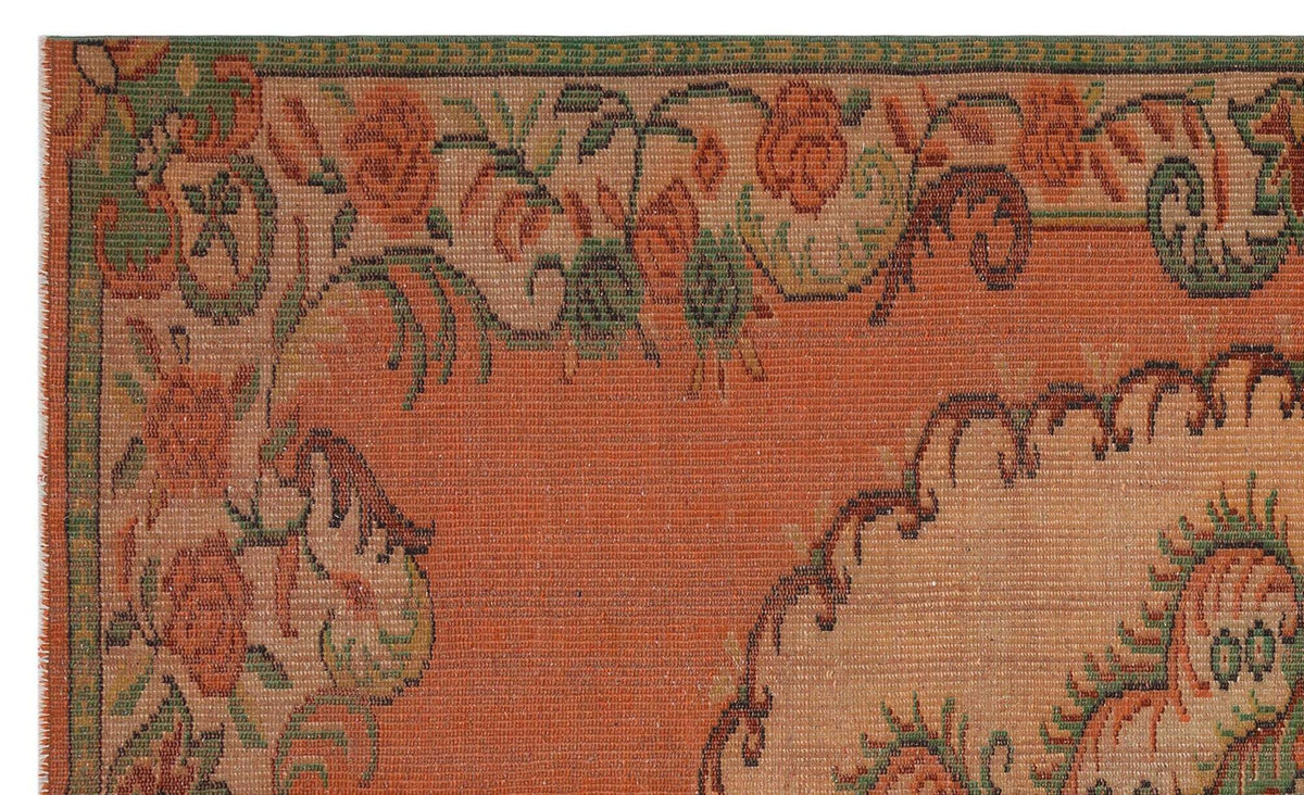Terracotta rug with a green and orange floral border and a central medallion pattern.