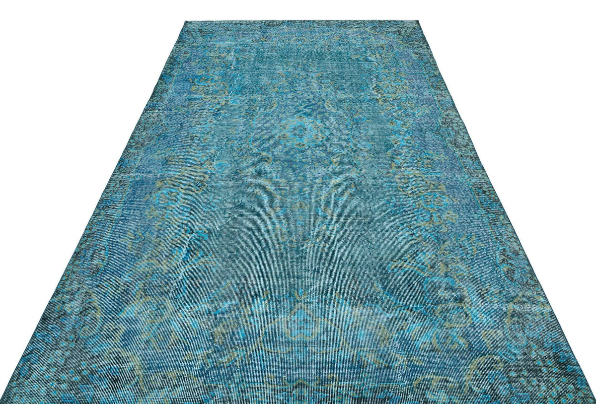 Teal and olive green distressed area rug with a traditional faded medallion pattern on a white background.
