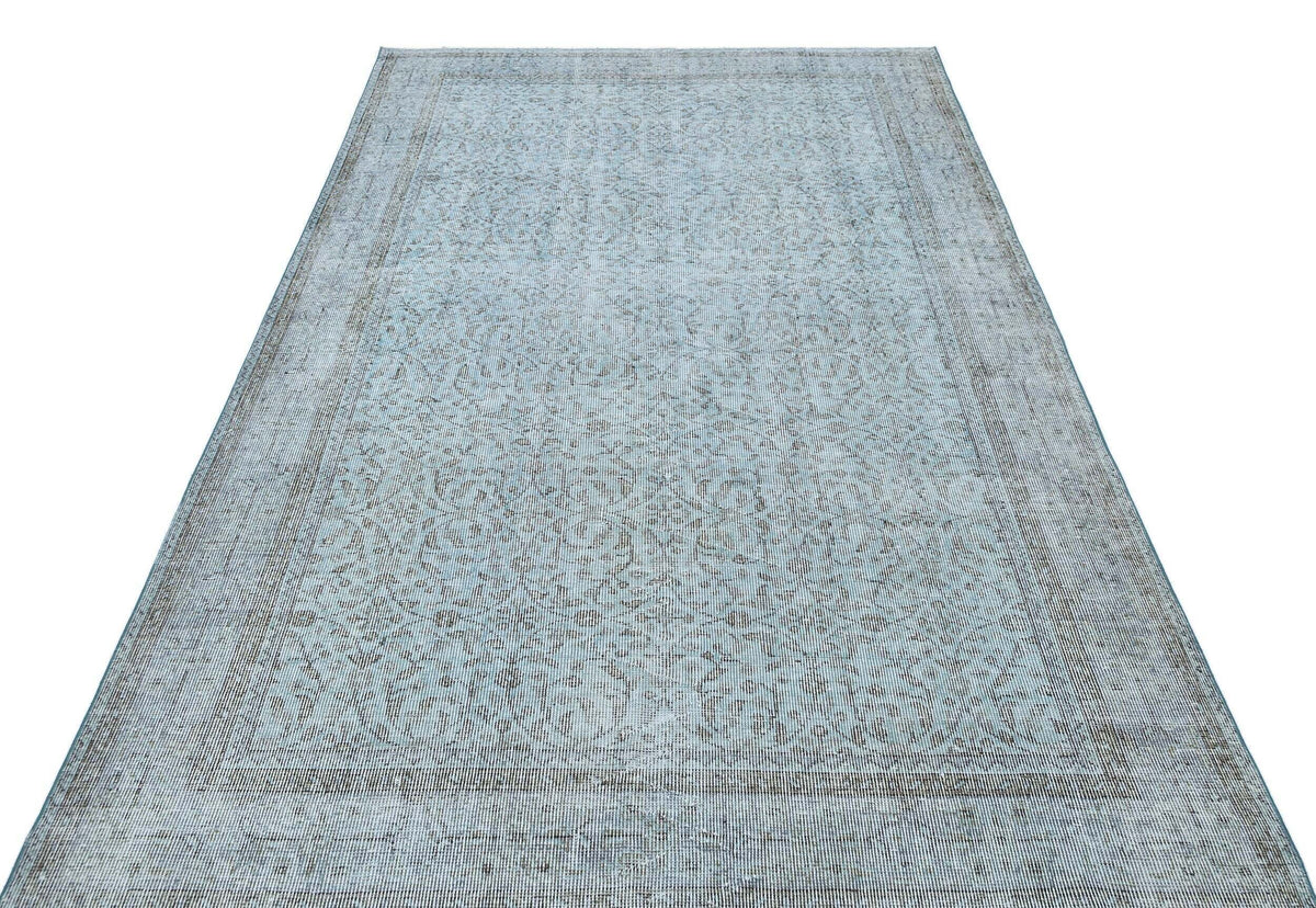 Light blue and grey distressed rug with a traditional floral medallion pattern on a white background.