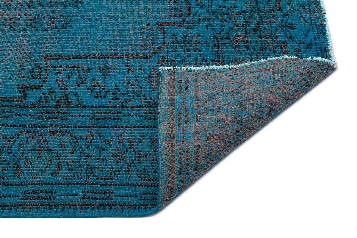 Teal and charcoal distressed traditional rug with a folded corner revealing the textured underside.