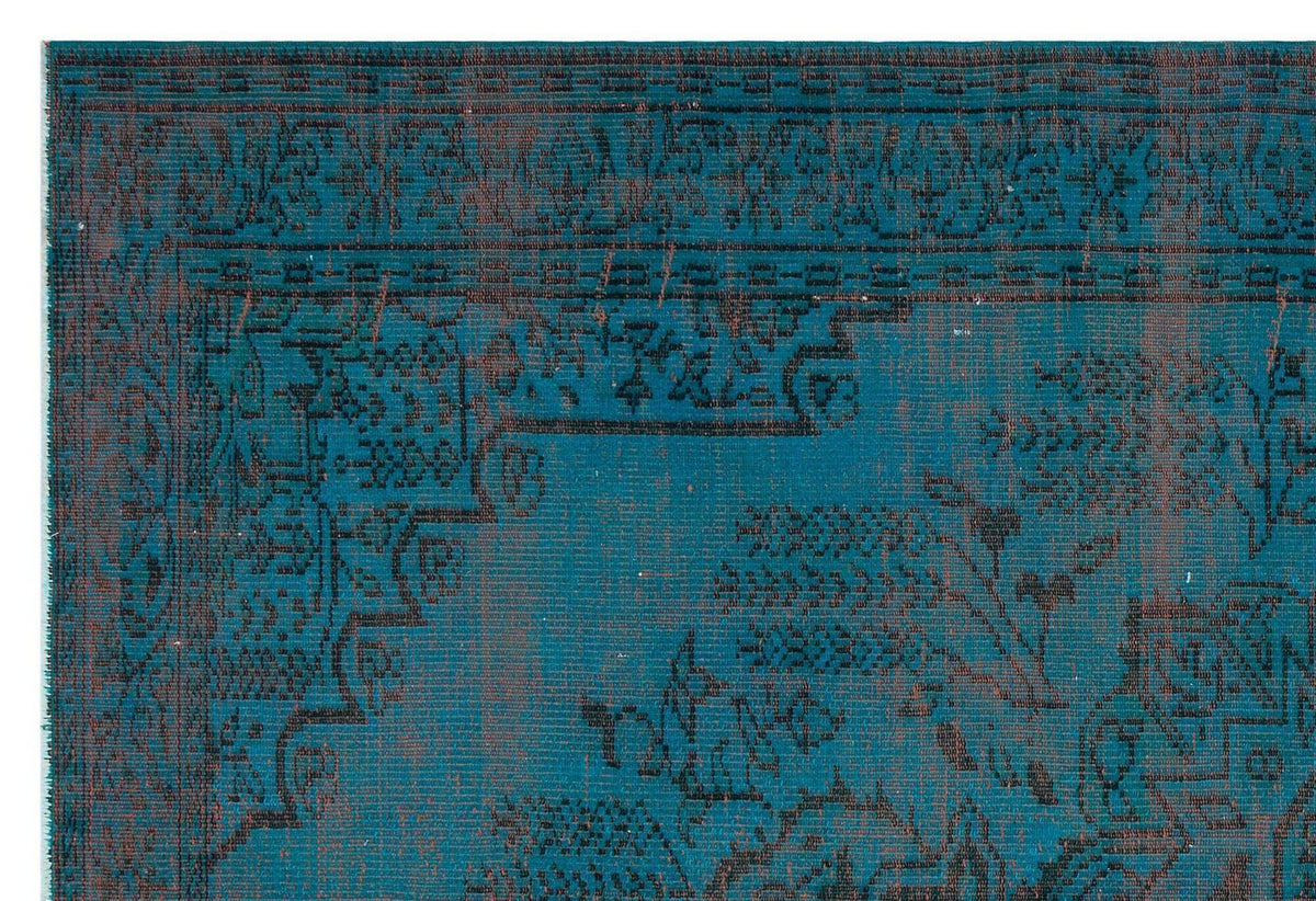Teal and black rug with a distressed traditional floral medallion pattern and a geometric border.