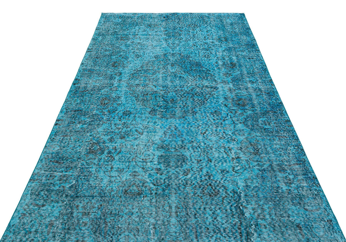 Bright turquoise runner rug with a distressed, dark blue traditional medallion pattern on a white background.