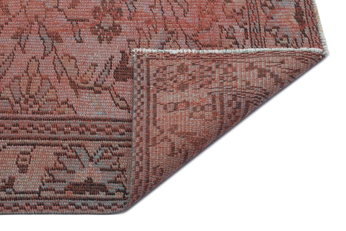 Load image 1 in gallery view. Terracotta and brown vintage-style rug with a distressed floral pattern, shown with a corner folded over.