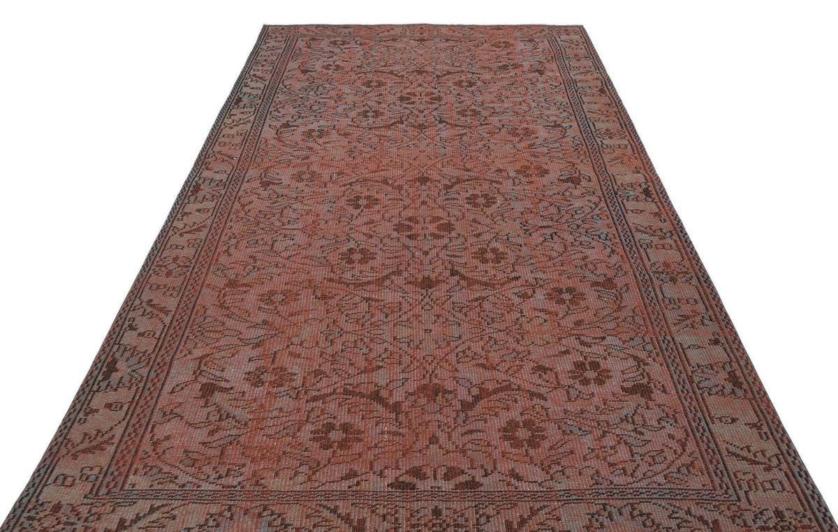 Terracotta and brown vintage-style rug with a repeating floral medallion pattern and a detailed border on a white background.