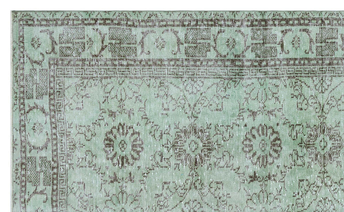 Mint green and brown distressed rug with a traditional floral medallion pattern and geometric border.
