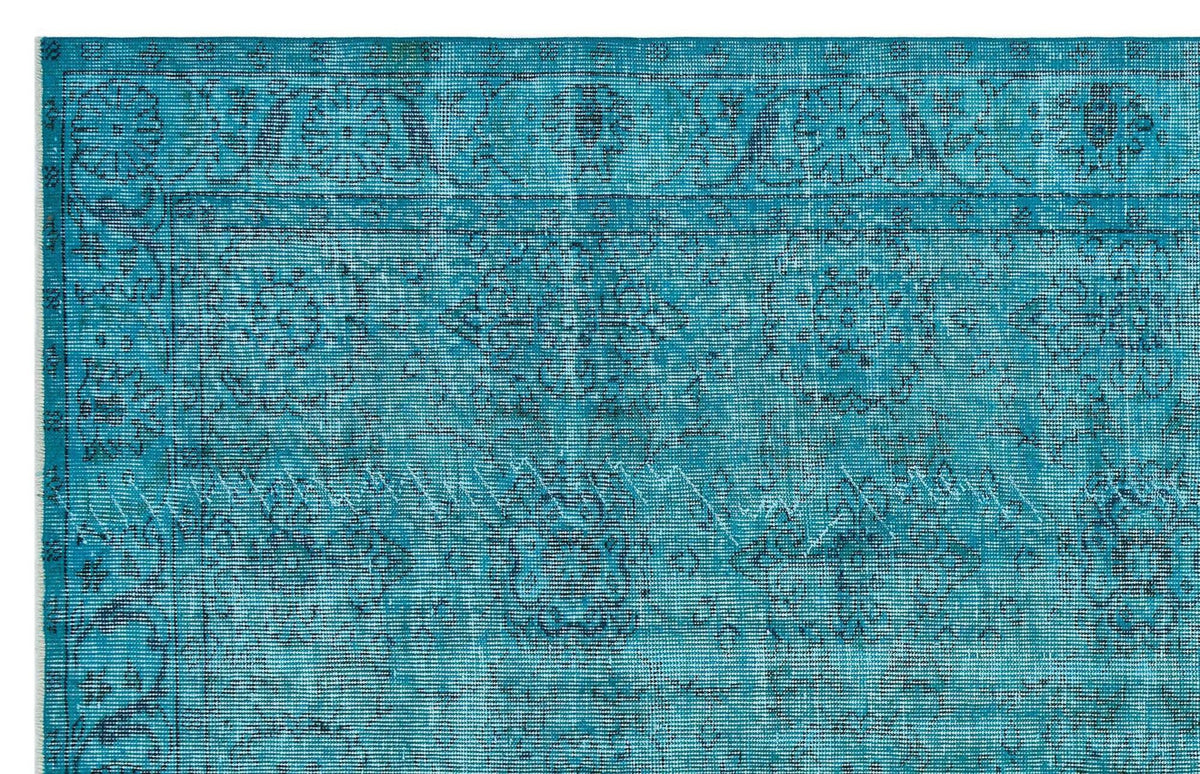 Teal distressed rug with a traditional floral medallion border and faded geometric pattern.