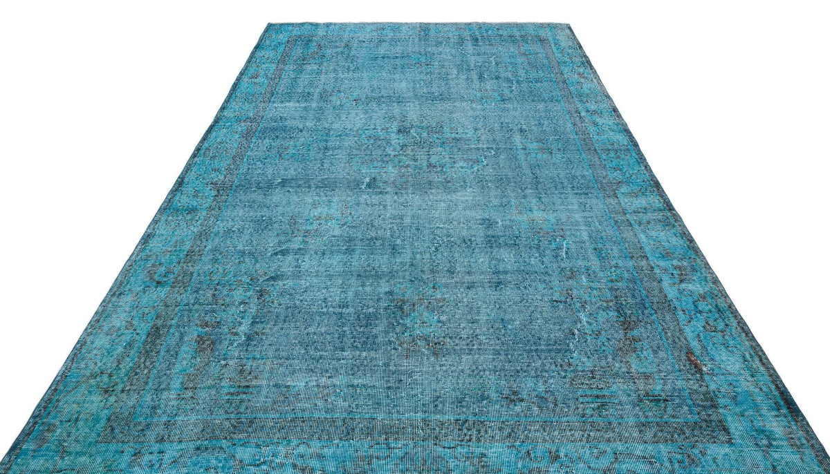 Distressed turquoise and black overdyed rug with a traditional medallion pattern on a white background.