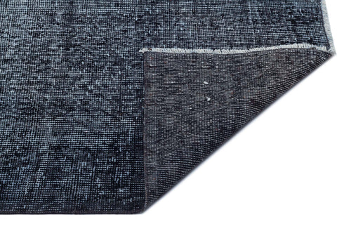Load image 1 in gallery view. Charcoal and navy blue distressed area rug with a folded corner revealing the dark woven backing and fringe edge.