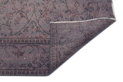 Load image 1 in gallery view. Dark purple distressed rug with a faded floral pattern and a folded corner showing the textured backing.