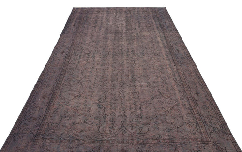 Load image 1 in gallery view. Dark brown distressed rug with a faded traditional floral pattern and a bordered edge on a white background.