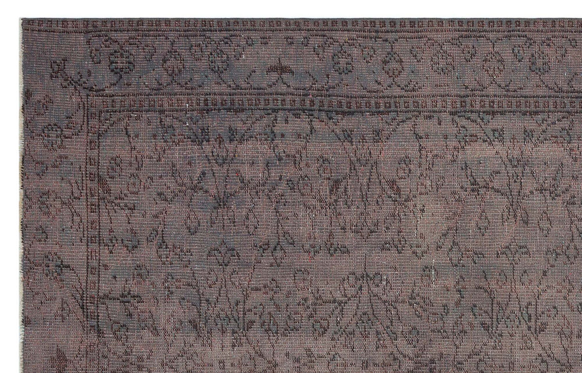 Dark charcoal and brown distressed rug with a traditional floral border and central vine pattern.