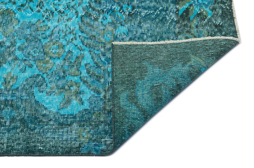 Load image 1 in gallery view. Turquoise and dark green distressed floral rug with a folded corner showing the woven backing.