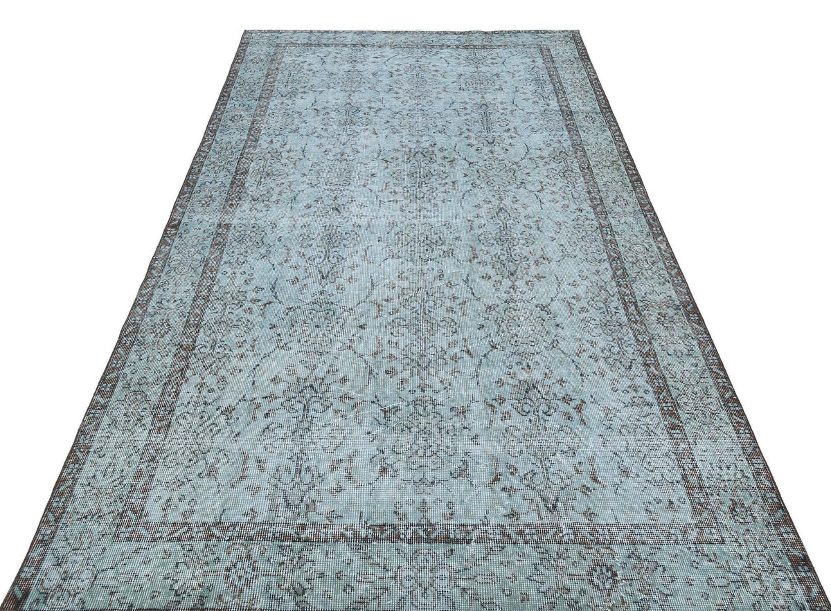 Light blue and dark brown distressed rug with a traditional floral medallion pattern and a wide decorative border.