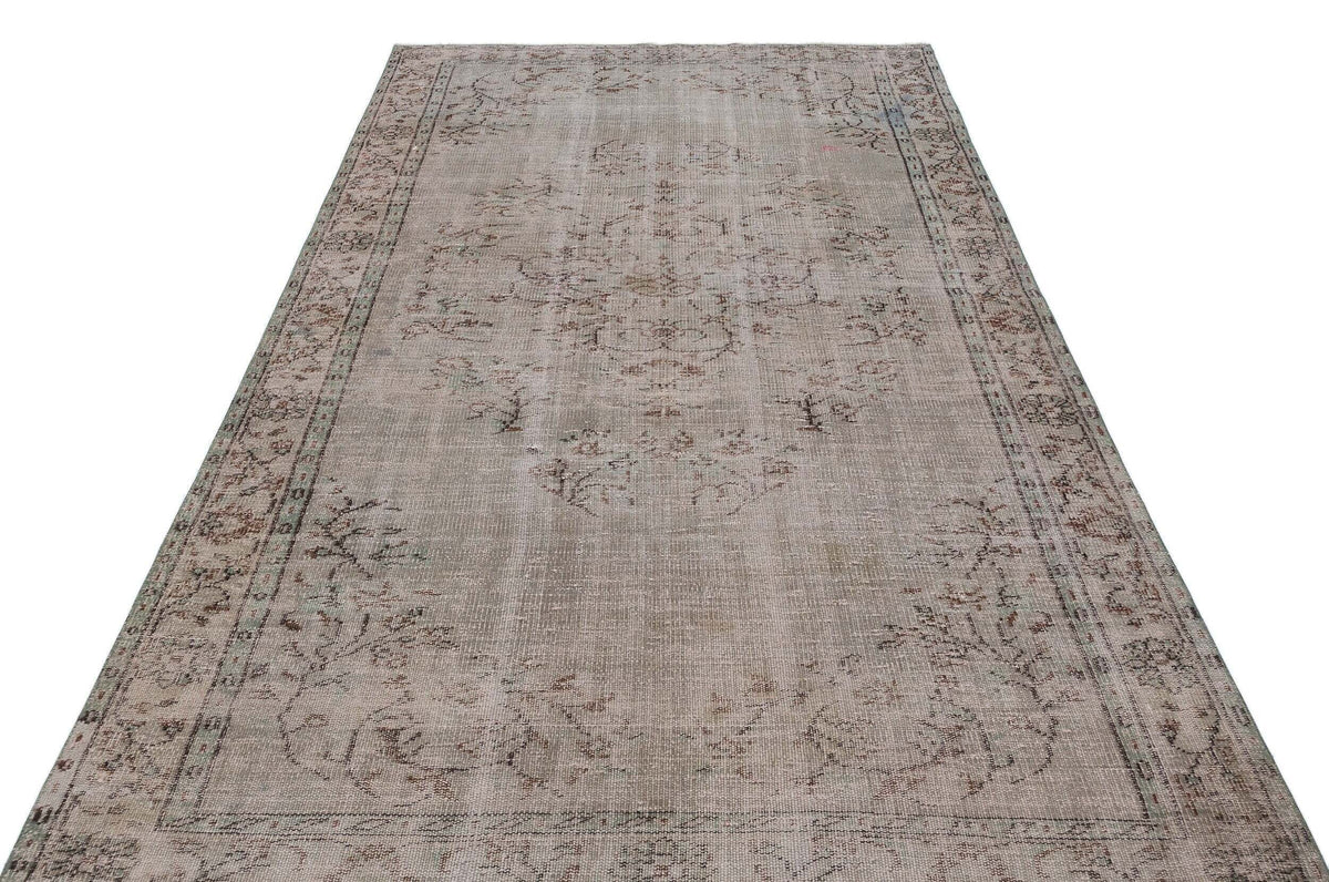 Distressed beige and grey vintage-style rug with a faded central medallion and ornate border on a white background.