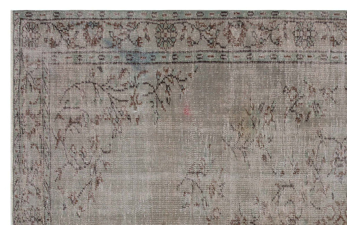 Distressed taupe and sage green rug with a faded traditional floral border and central medallion motif.