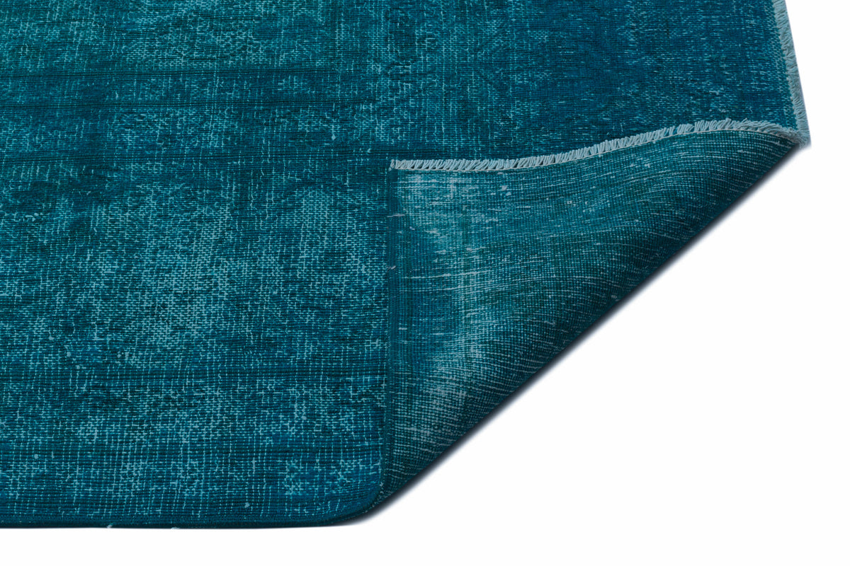 Teal distressed-style rug with a woven texture and a folded corner showing the underside.