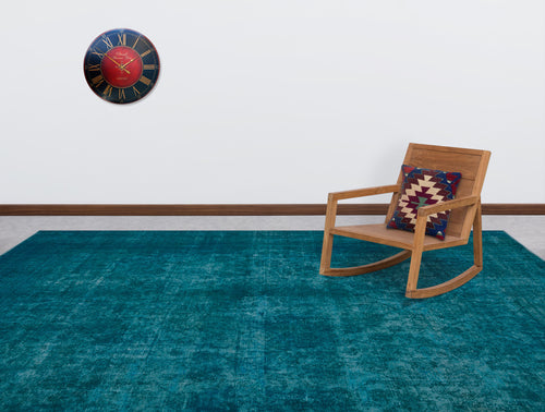 Load image 1 in gallery view. Teal distressed-texture rug in a room with a wooden rocking chair and wall clock.