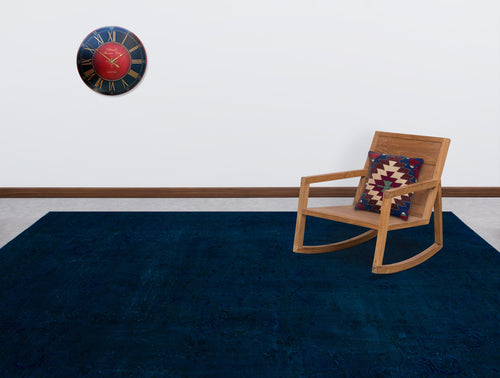 Load image 1 in gallery view. Solid navy blue rug with a subtle, tonal traditional pattern, styled in a room with a wooden rocking chair and wall clock.