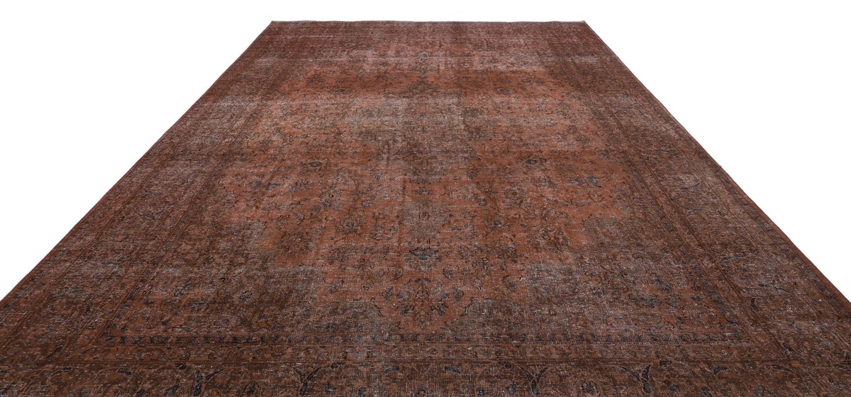 Distressed rust-colored rug with a faded traditional floral medallion pattern and dark blue border details.