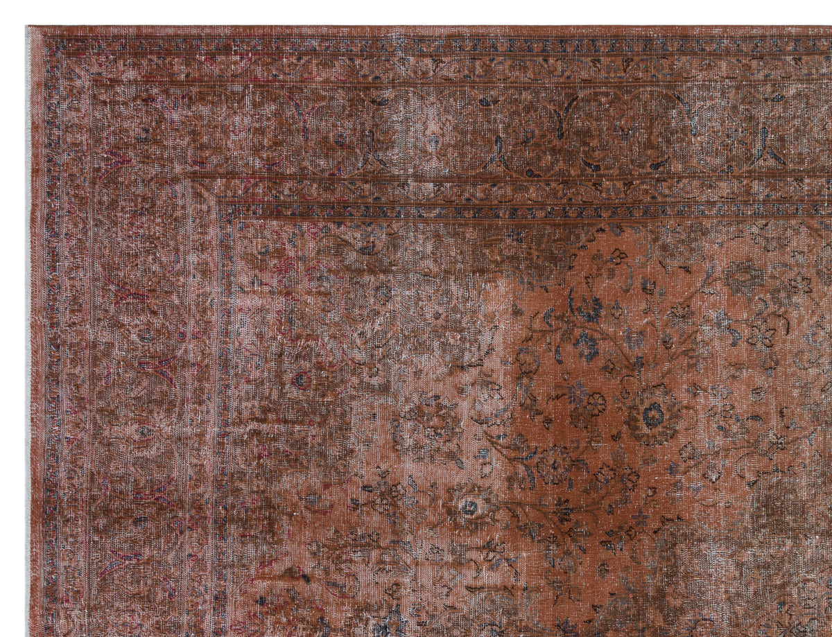 Distressed rust-colored rug with a traditional floral medallion pattern and a dark, intricate border.