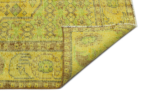 Load image 1 in gallery view. Yellow and lime green vintage-style rug with a distressed geometric pattern, showing a folded corner on a white background.