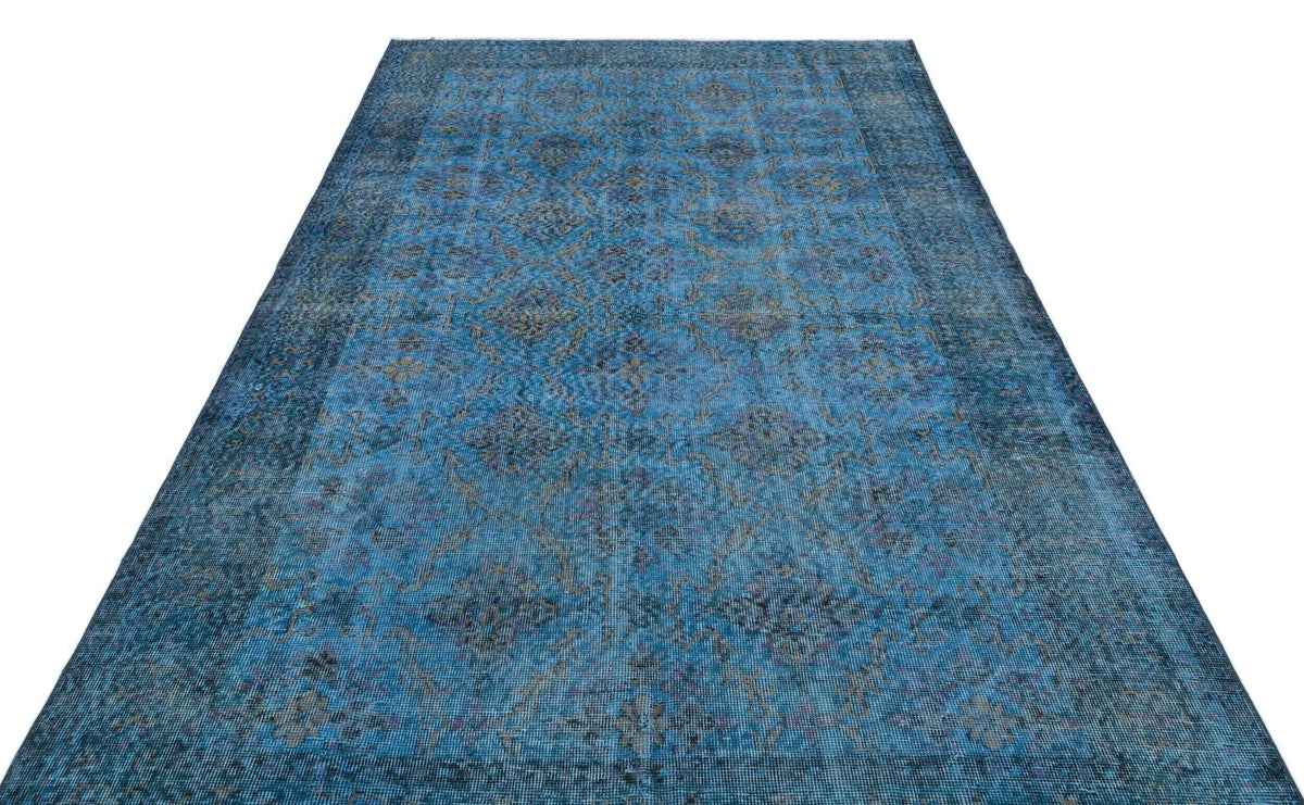 Blue distressed traditional rug with a faded floral medallion pattern on a white background.