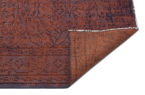 Load image 1 in gallery view. Rust and charcoal distressed rug with a subtle floral pattern, shown with a corner folded over on a white background.